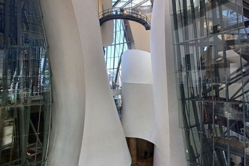 A modern architectural structure with curved white walls and a glass facade. 3