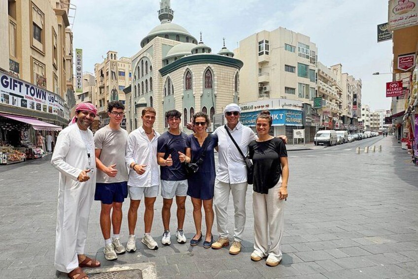 A group of people standing on a paved street with buildings and shops in the background. 3