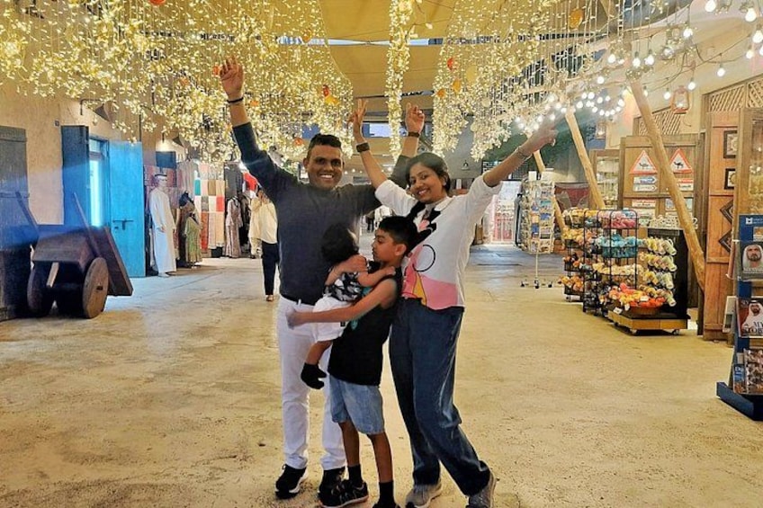 A family of four in a market with hanging lights and various stalls. 2
