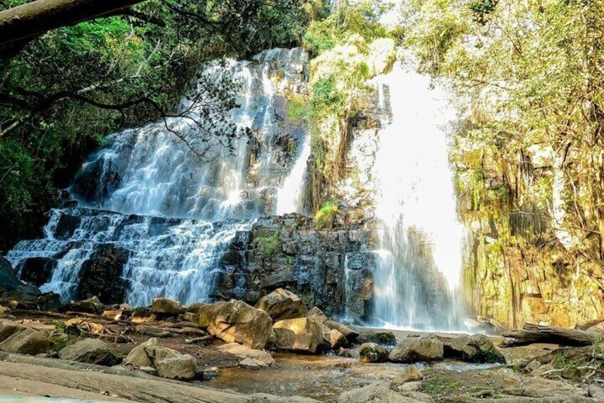 Een waterval die over rotsen stroomt in een bebost gebied. 2