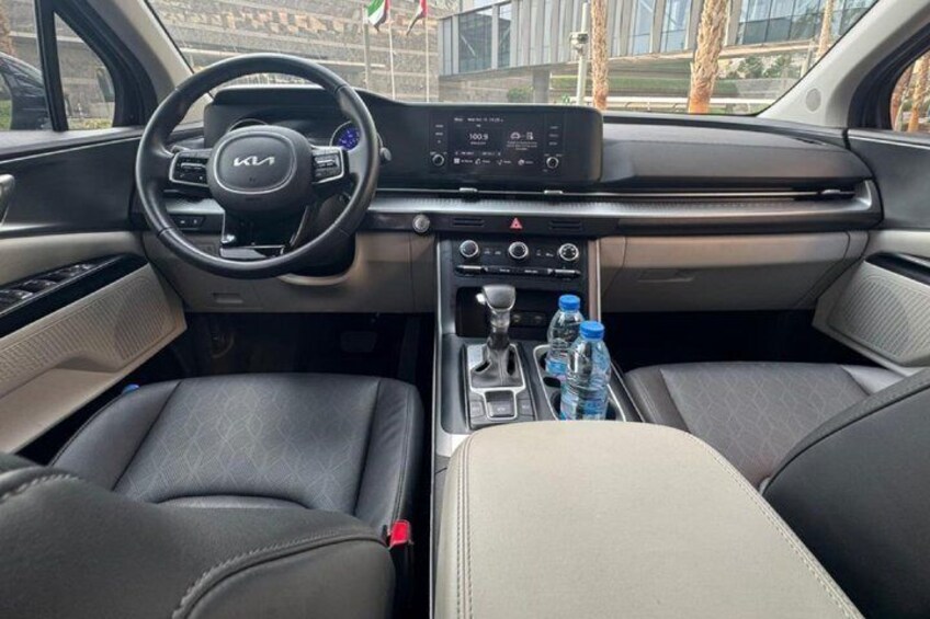 El interior de un coche con volante, salpicadero, palanca de cambios y dos botellas de agua. 3
