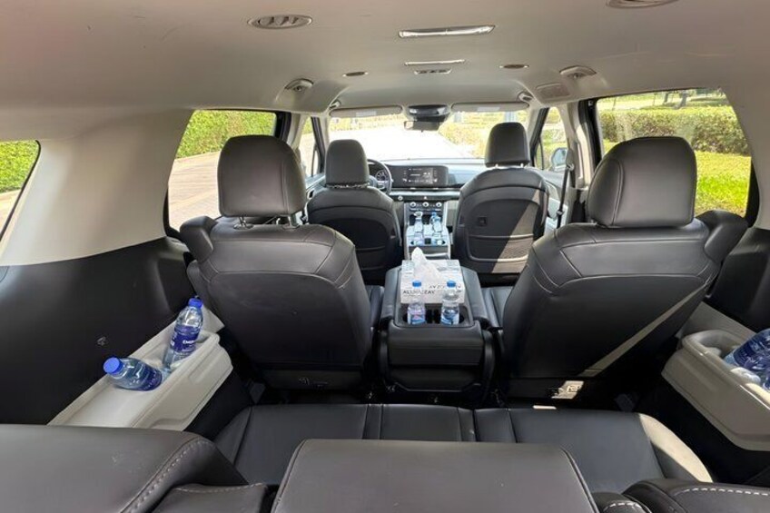 Interior de automóvil con cuatro asientos de cuero negro, una consola central con portavasos y vista trasera del tablero. 2