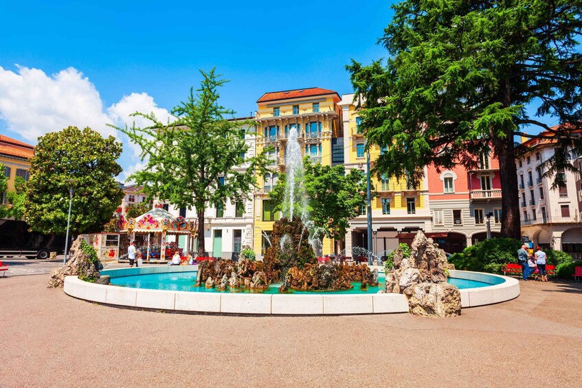 A fountain surrounded by a circular walkway, with colorful buildings in the background. 4