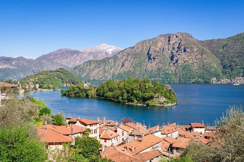 Ein See, umgeben von Bergen, eine kleine Insel und ein Dorf mit roten Dächern. 4