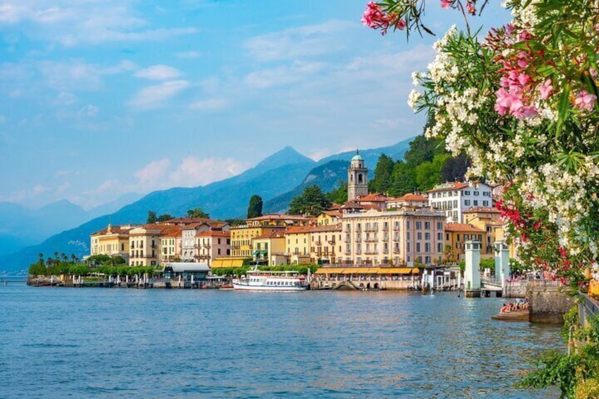 A lakeside town with colorful buildings, a boat docked at the pier, and mountains in the background. 1