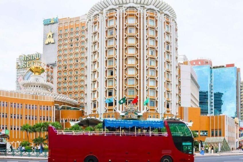 A red bus with a blue canopy, a casino building, and a tall hotel with a distinctive facade. 1