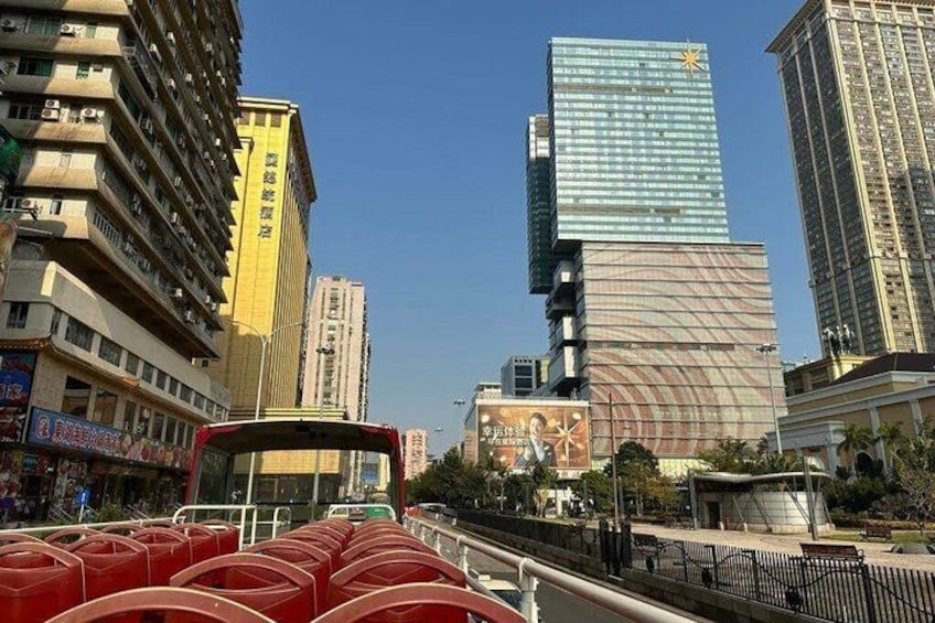 A city street with modern buildings, a bus, and a pedestrian walkway. 4