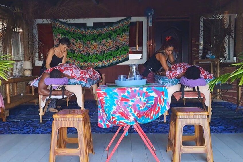 Dos personas realizando un masaje sobre una cama con una manta colorida. 3
