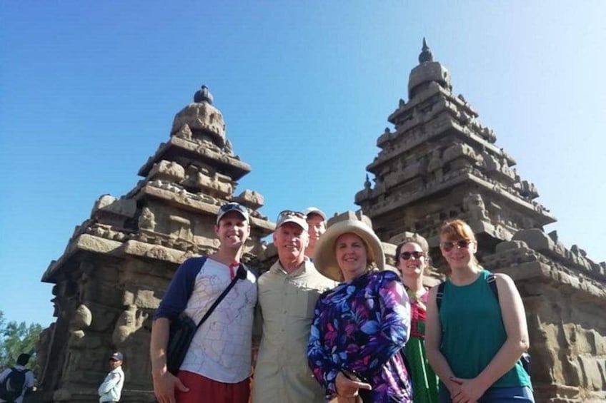 A group of people standing in front of a large stone temple with intricate carvings and multiple tiers. 2