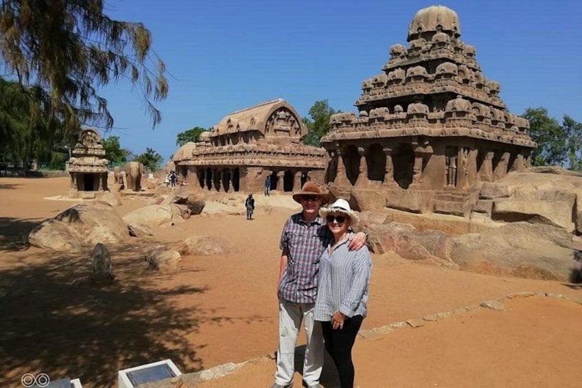 Ancient stone structures with intricate carvings, a clear sky, and a few people in the foreground. 5