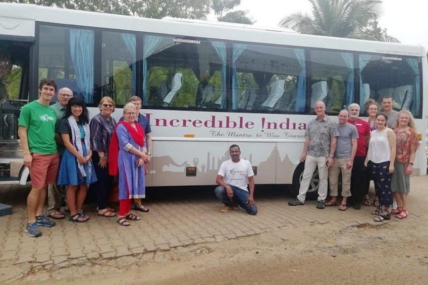 A group of people posing in front of a bus with 'Incredible India' written on it. 3