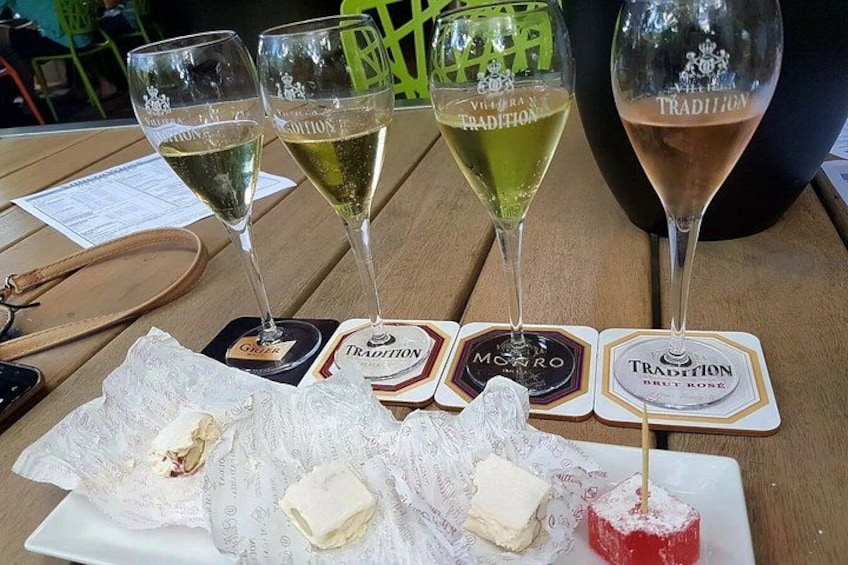 Tre glas vin, en tallrik med ost och kex samt underlägg med varumärkeslogotyper. 1
