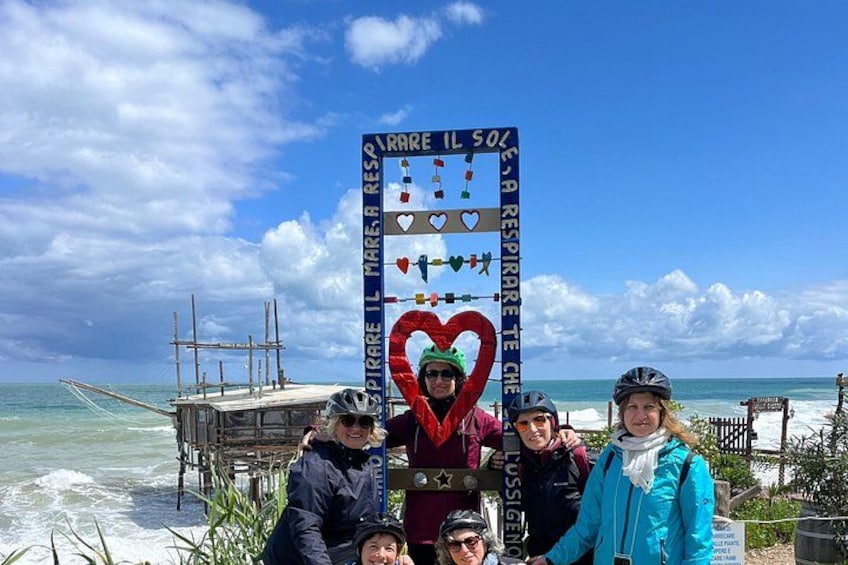 A group of people posing in front of a sign with a heart symbol and text. 1