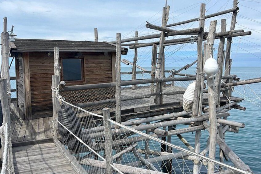 A wooden dock with a cabin, surrounded by a netted railing, and a buoy in the water. 2