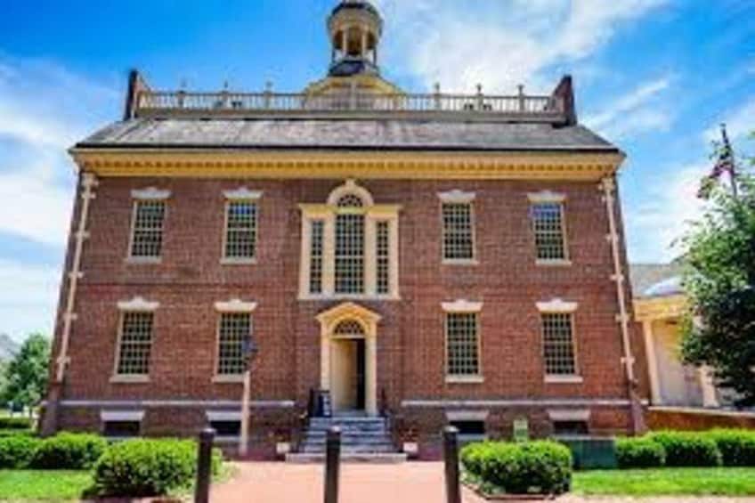 A brick building with a central entrance, a dome, and a flagpole. 5