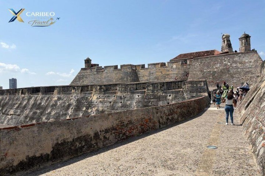 A historic stone wall with a pathway leading up to a fortified structure. 3