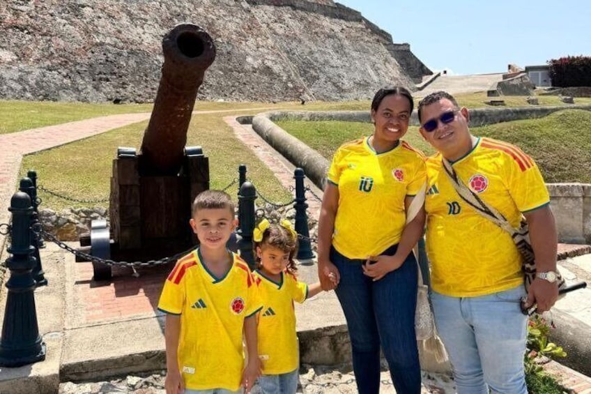 A family in yellow jerseys standing in front of a cannon. 5