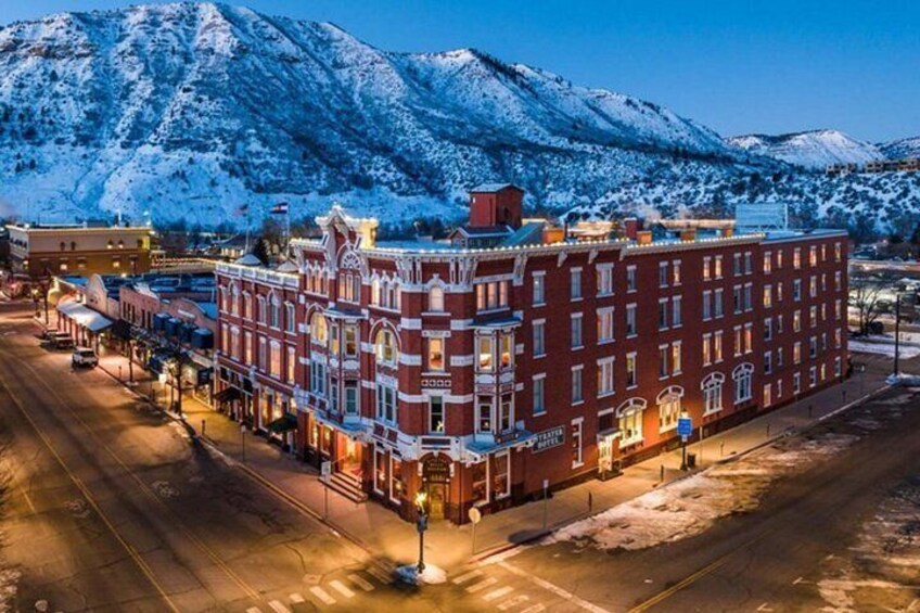 Una cordillera nevada al fondo, un edificio de ladrillo rojo con detalles ornamentales, y una calle bordeada de tiendas. 5