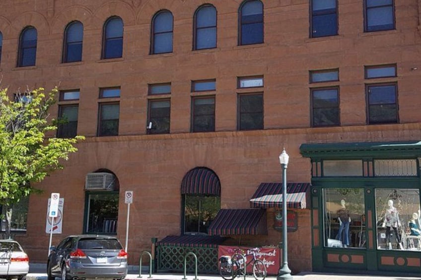 A brick building with multiple windows, a covered entrance, and a bus stop with a shelter. 2