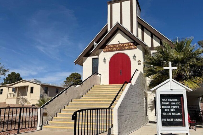 A church with a red door, a cross, and a signboard with a message. 3