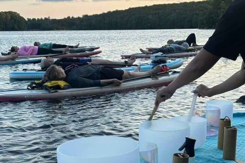 People on paddleboards in a body of water, with a person paddling nearby. 2