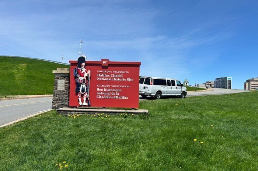Ein rotes Schild mit einer historischen Person und Text, der Besucher zur Halifax Citadel National Historic Site willkommen heißt. 4