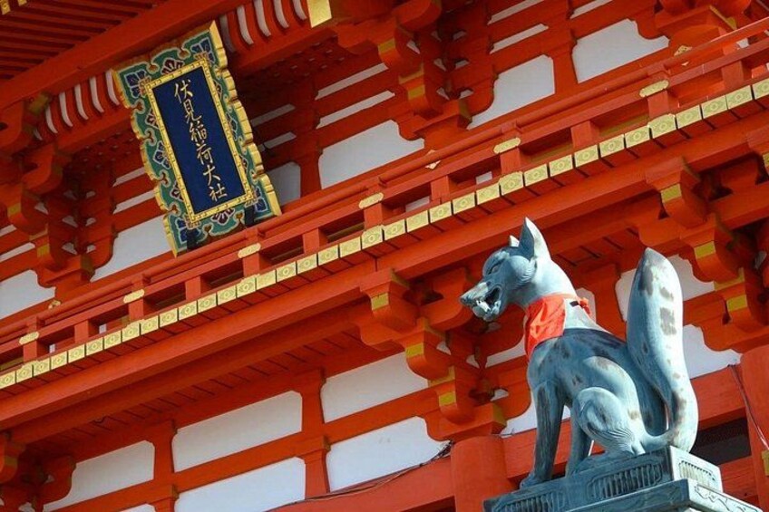 Un torii traditionnel japonais, surmonté d’une statue de loup portant un collier rouge. 2