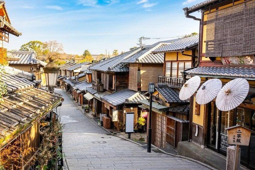 Een traditionele Japanse straat met houten gebouwen, pannendaken en hangende parasols. 3