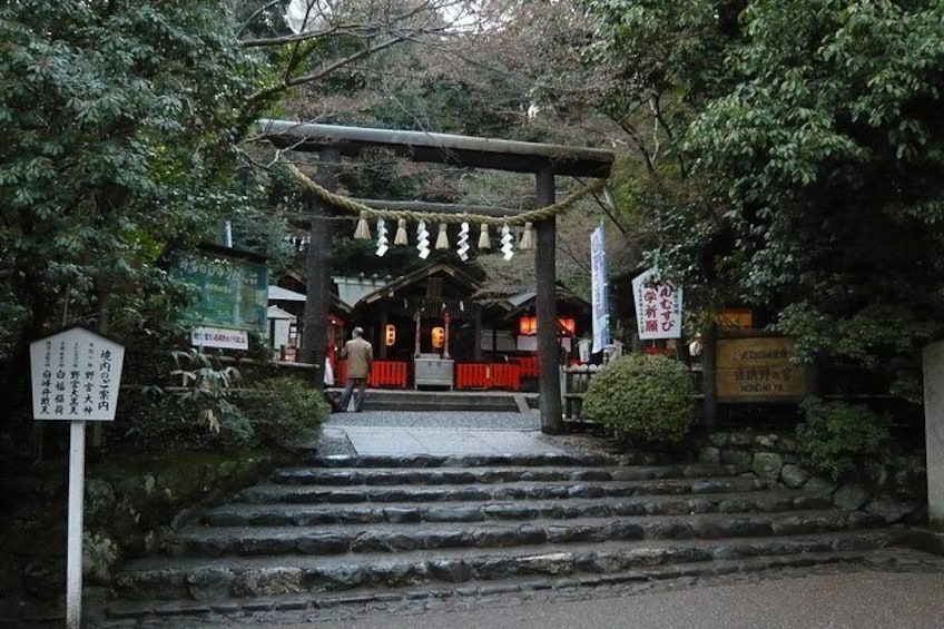 A traditional Japanese shrine entrance with stone steps, a wooden torii gate, and signage. 2