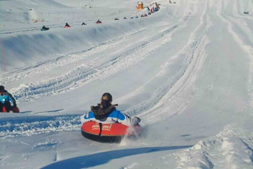 A person sledding down a snowy slope on a red sled with 'FARLORES' written on it. 2