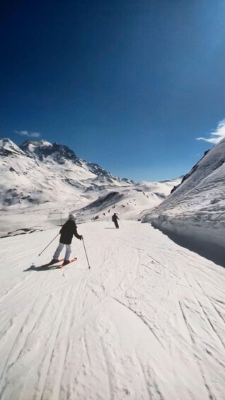 A snowy mountain slope with skiers descending. 1