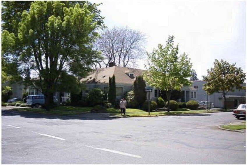 A residential street with houses, parked cars, and a person walking on the sidewalk. 3