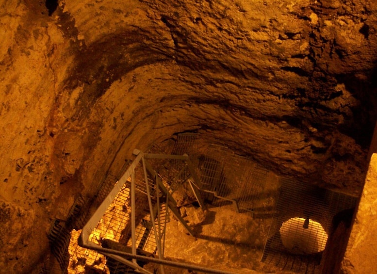 A cave with a metal staircase leading down to a circular opening. 5