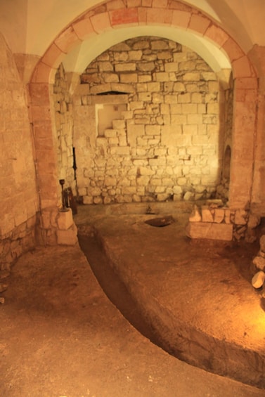An ancient stone structure with a brick archway and a central hearth. 3