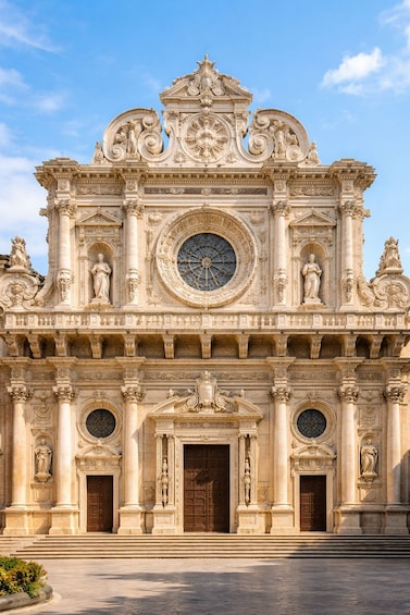 A grand, ornate building with a large circular window and statues. 1