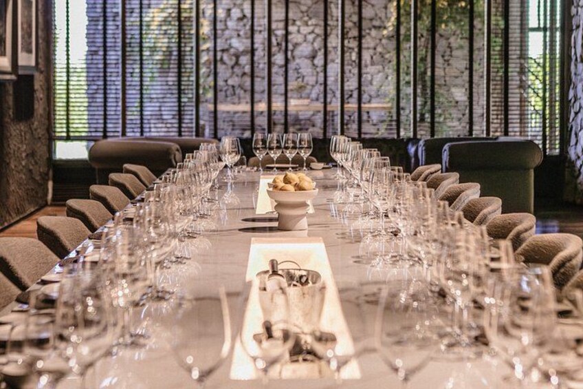 A long dining table set with multiple wine glasses and plates, surrounded by chairs. 5