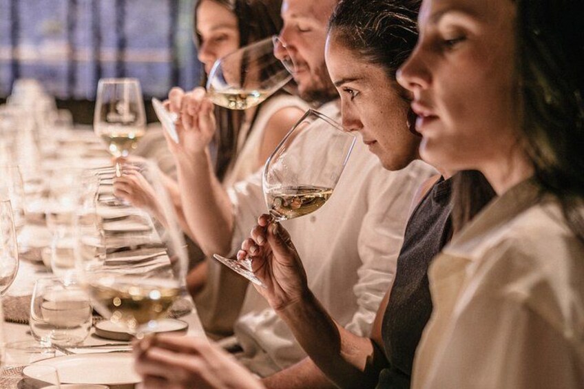 A group of people seated at a table, holding wine glasses. 3