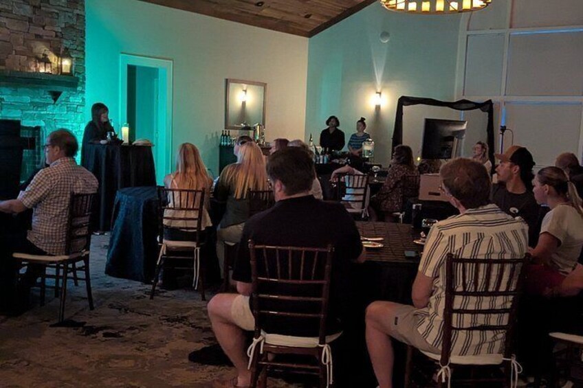 A group of people seated at tables in a dimly lit room with a brick wall and a fireplace. 4