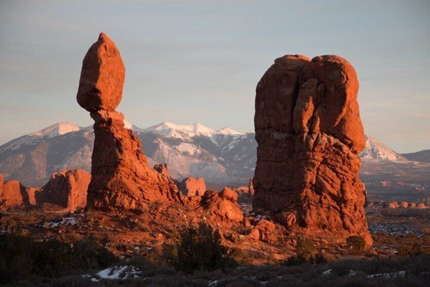 A desert landscape with red rock formations and a snow-capped mountain in the background. 4