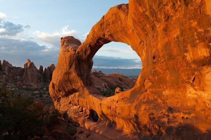 A large rock formation with a natural arch and surrounding desert landscape. 5