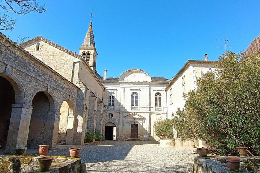 A historic building with arches, a church steeple, and a cobblestone courtyard. 5