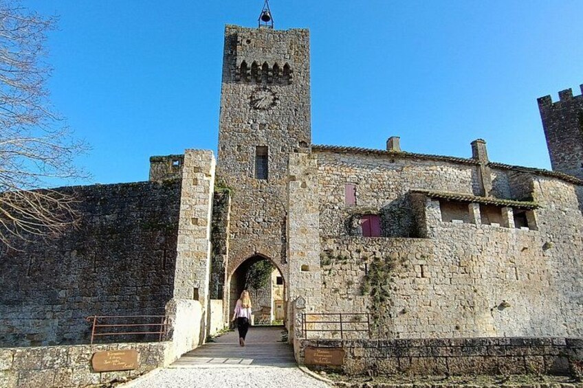 A historic stone building with a clock tower, an arched entrance, and a paved pathway leading to it. 1