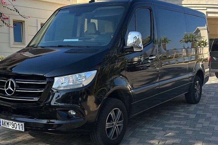 Una furgoneta negra Mercedes-Benz estacionada sobre una superficie pavimentada. 2