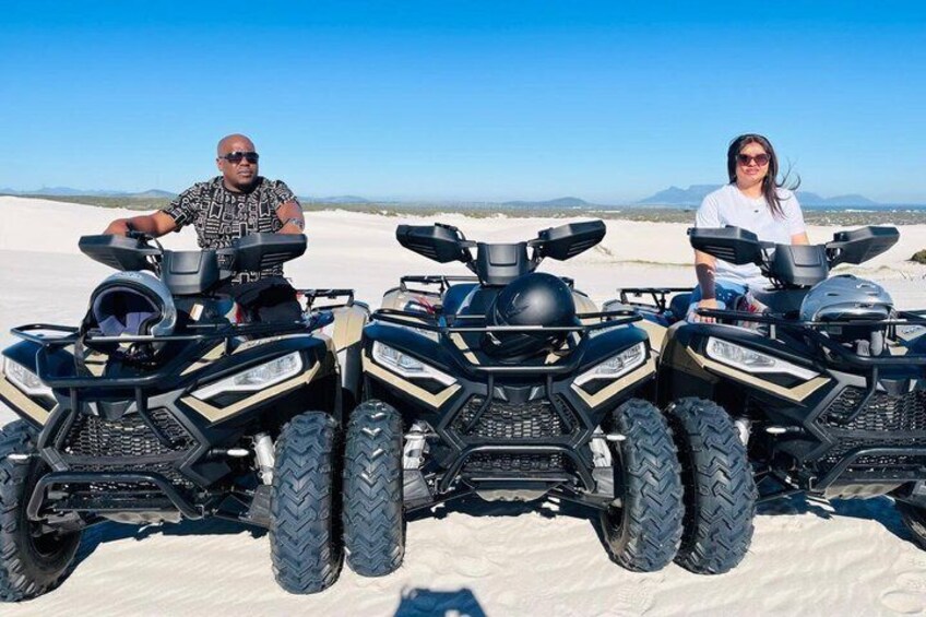 Three ATVs parked on a desert landscape with mountains in the background. 1