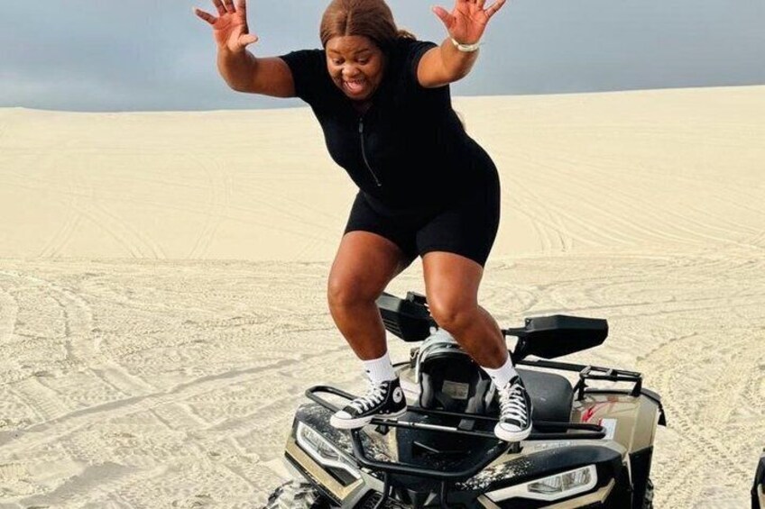 A person on a quad bike in a desert with sand dunes in the background. 5