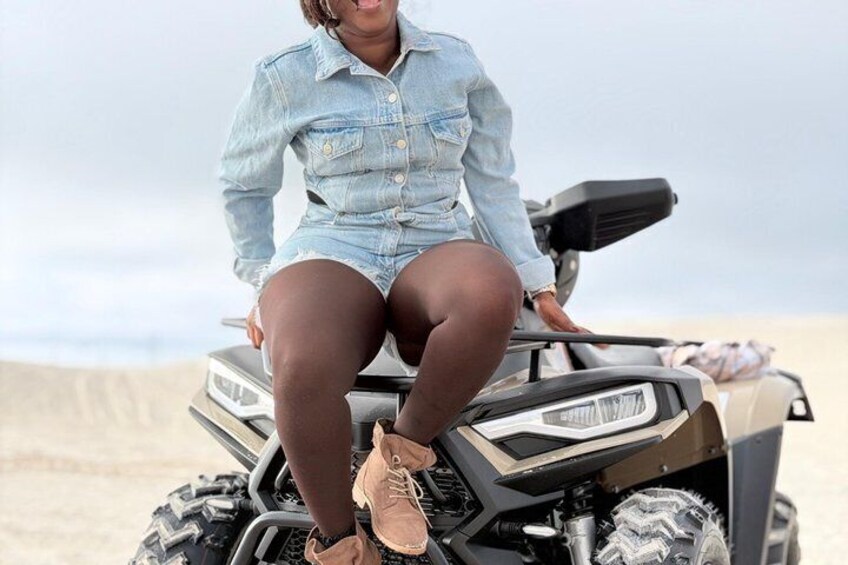 A person sitting on a quad bike on a sandy surface. 2