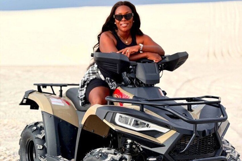 A person sitting on a quad bike in a desert landscape. 4