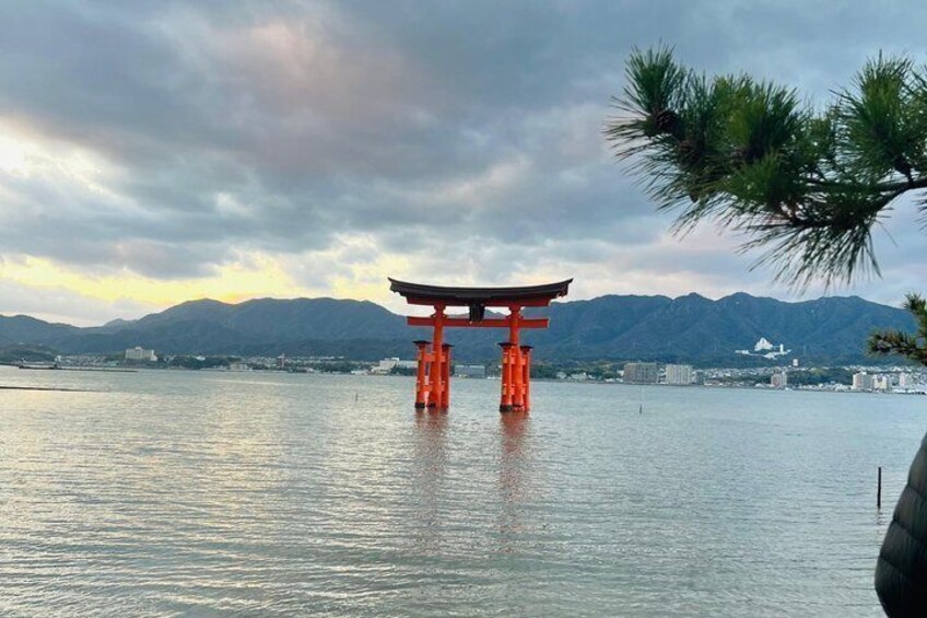A traditional Japanese torii gate in the water, surrounded by mountains and buildings. 1