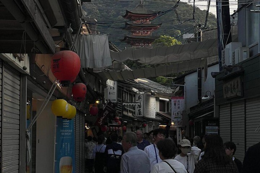 A narrow street with traditional buildings, red lanterns, and a crowd of people. 3