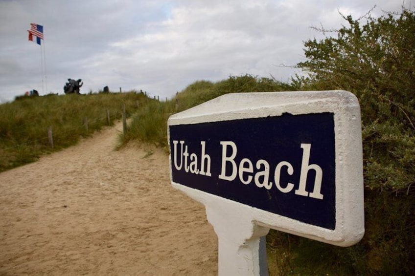 En skylt med texten ”Utah Beach” och en sandstig som leder ner till stranden. 5